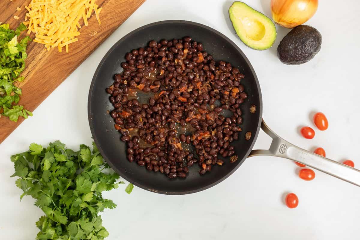 Schwarze Bohnen Taco Füllung Schwarze Bohnen in einer Sauteuse, nachdem sie mit Salsa geköchelt wurden.
