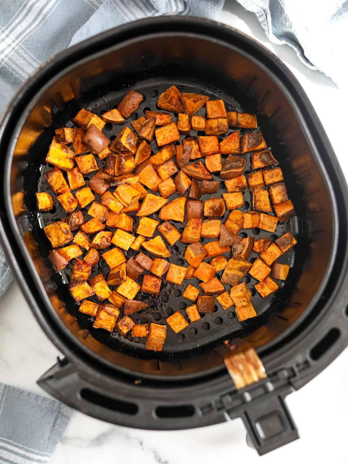 Süßkartoffel in der Heißluftfritteuse Heißluftfritteusenkorb mit gewürfelten gerösteten Süßkartoffeln.