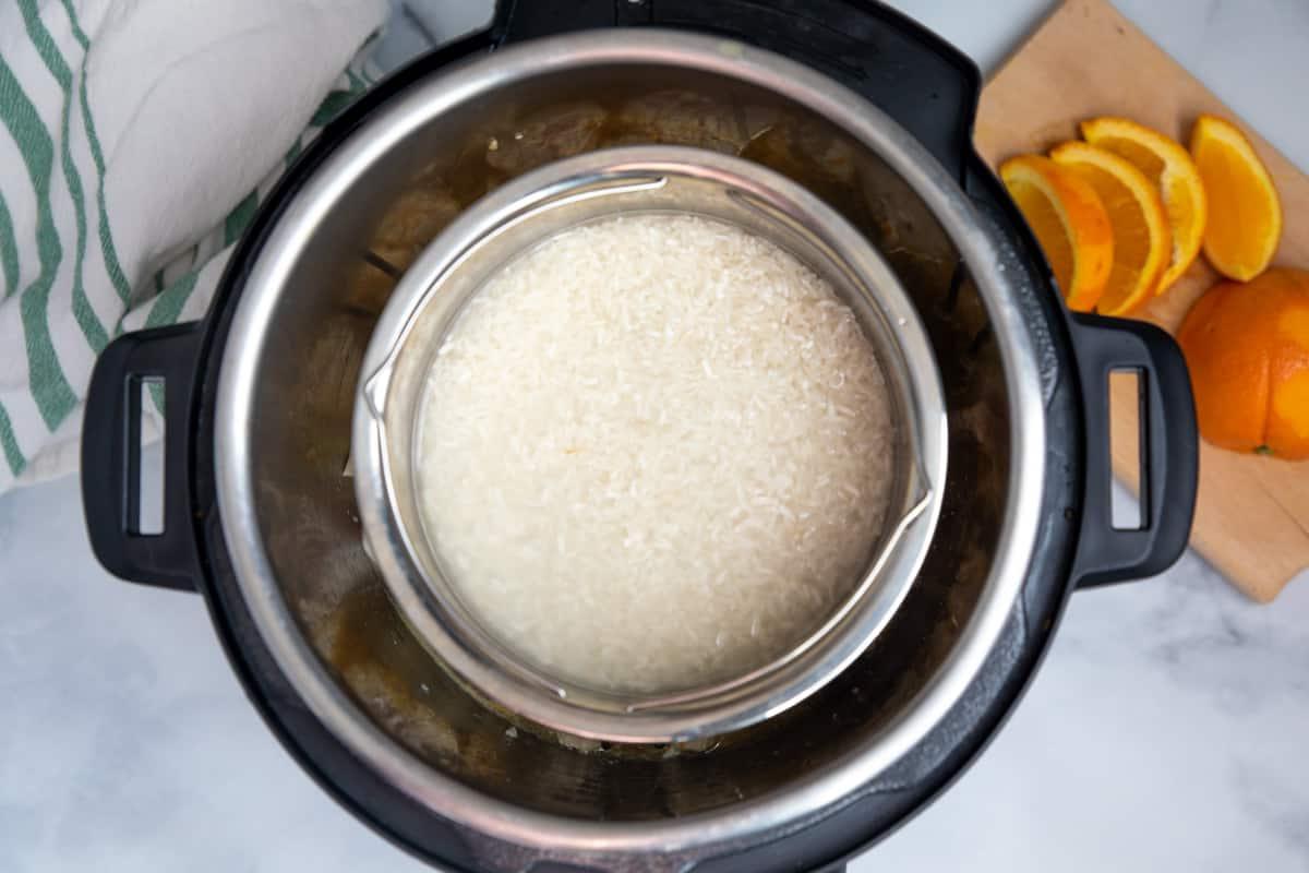 Reis in Edelstahlschüssel über Orangen-Hähnchen im Instant Pot.
