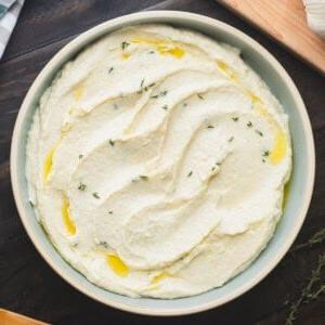 Das beste Pastinakenpüree 2 Eine Schale mit cremigem Pastinakenpüree mit Meerrettich, beträufelt mit etwas Olivenöl und frischen Thymianblättern.