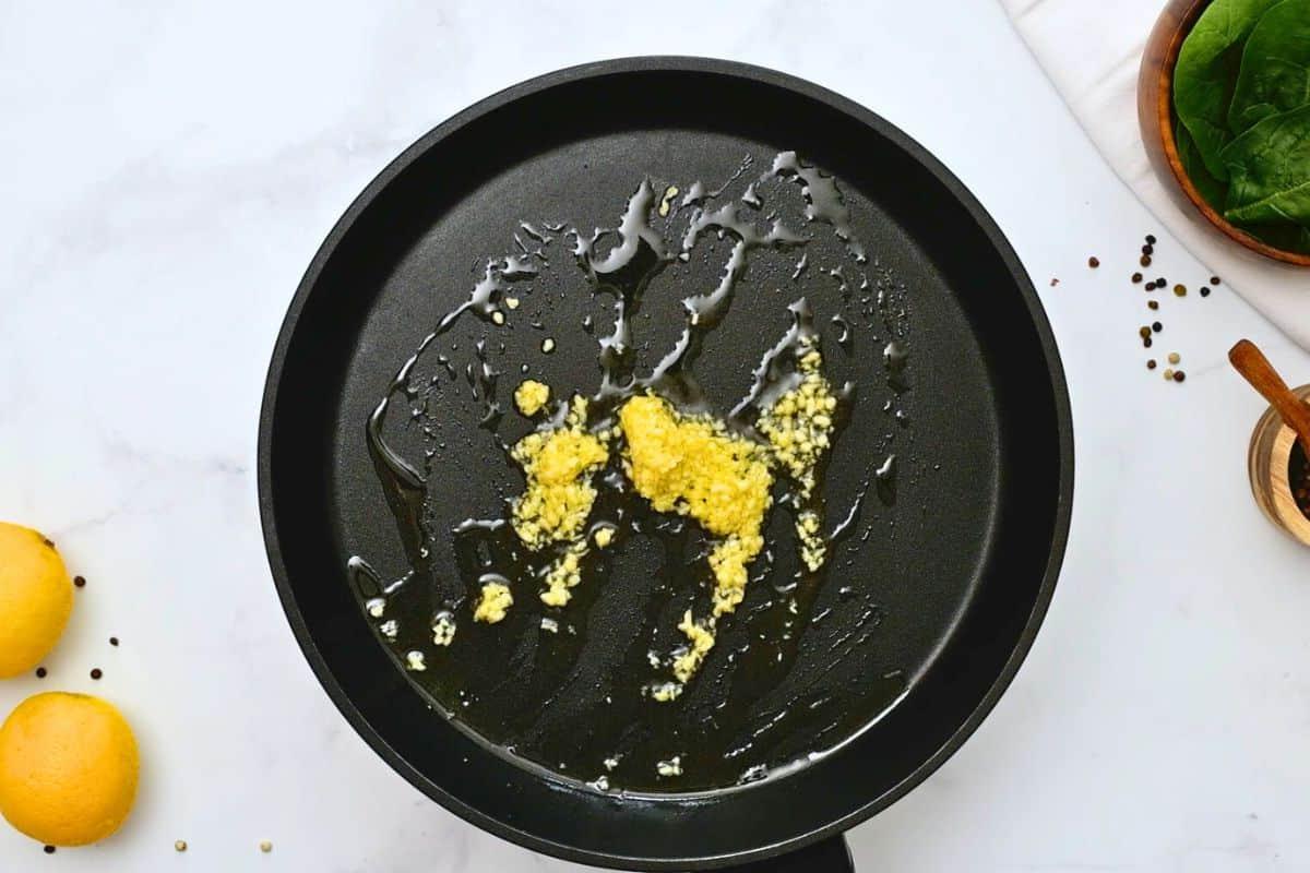 Leicht gerösteter Knoblauch in nativem Olivenöl extra in einer großen Bratpfanne.