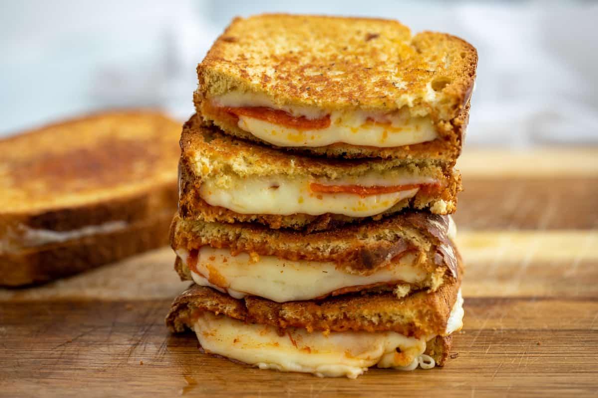 Aufgeschnittene Pizza Grilled Cheese Sandwiches auf einem Schneidebrett.