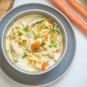 Schale mit cremiger Instant Pot Puten-Nudelsuppe, garniert mit frischer Petersilie.