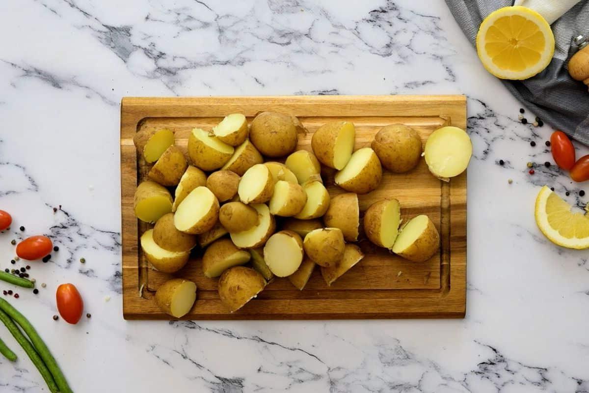Neuer Kartoffelsalat mit grünen Bohnen Gekochte Babykartoffeln auf einem Schneidebrett, halbiert.