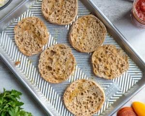 Blech mit halbierten English Muffins, bestrichen mit Knoblauchöl