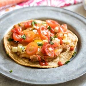 Southwestern Veggie Tostadas auf Silberplatte mit Tomaten und Mais belegt