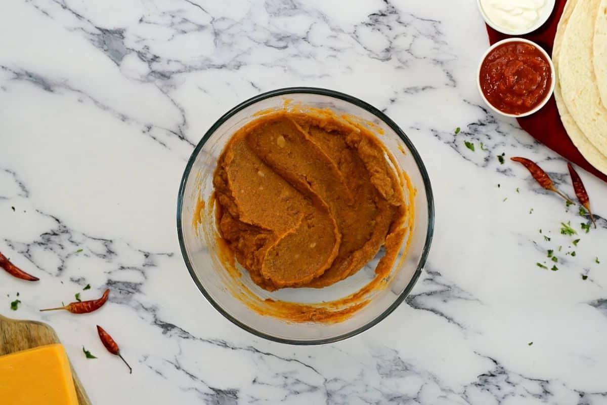 Schüssel mit Kürbispüree, Bohnenmus und Taco-Gewürzen, die miteinander vermischt wurden.