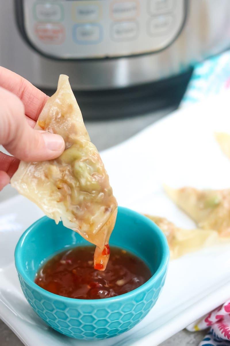 Potsticker wird in eine blaue Schale mit hausgemachter süßer Chilisauce getaucht.