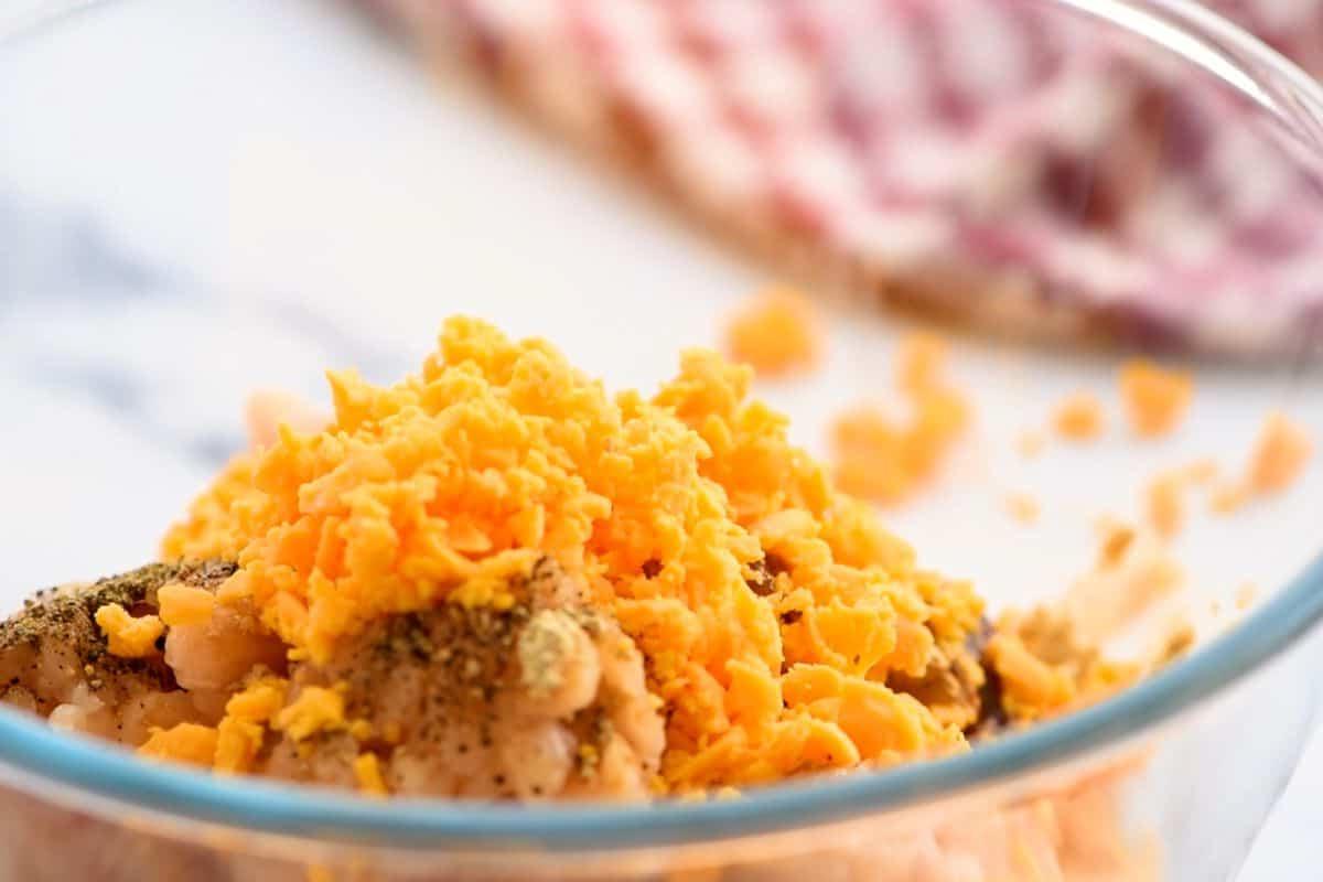 Cheddar cheese added to ground chicken in mixing bowl.