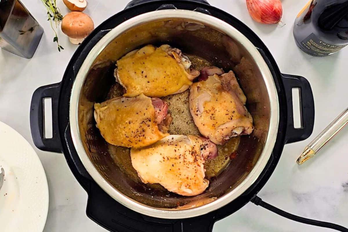Angebratene Hähnchenschenkel im Innentopf für Coq au Vin.