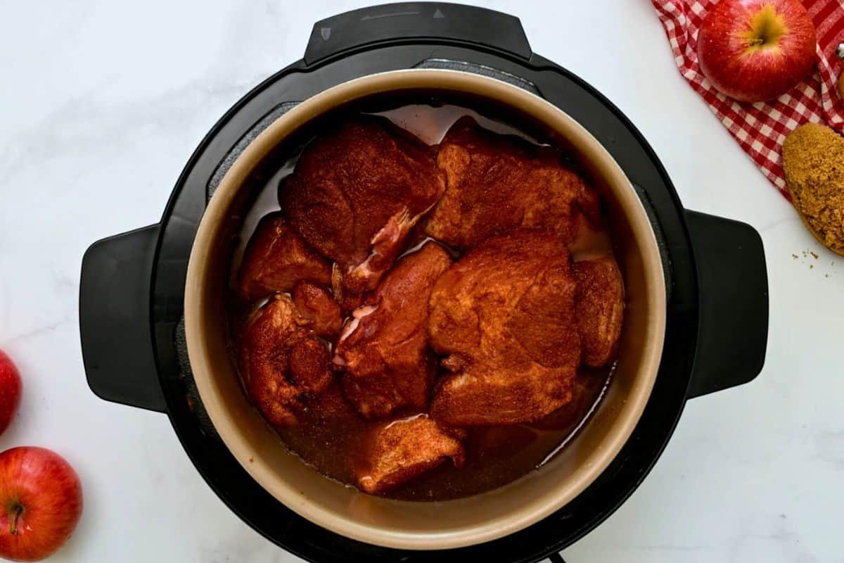 Gewürfeltes und gewürztes Schweinenacken in den Innentopf mit Apfelsaft und flüssigem Raucharoma.