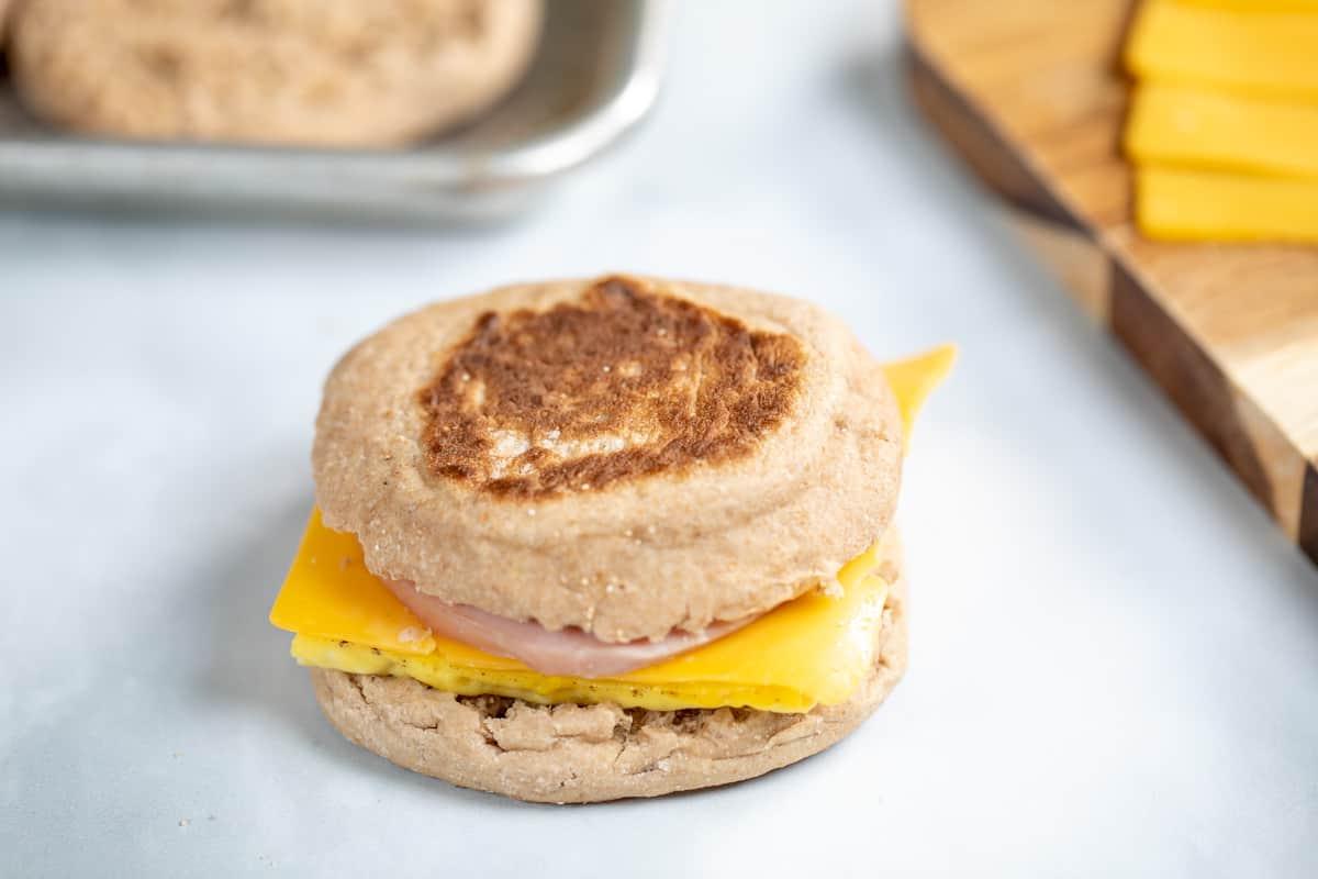 Zusammengestelltes Ei-, Schinken- und Käse-McMuffin-Sandwich auf der Arbeitsplatte.