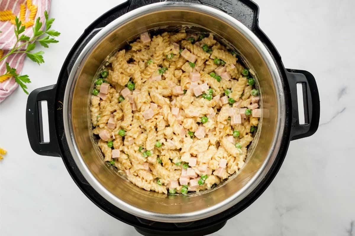 Instant Pot mit fertig gekochten Nudeln, Erbsen und Schinken in cremiger Sauce.