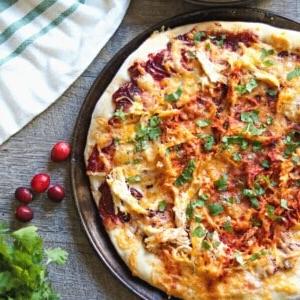 Pizza mit Truthahn und Preiselbeer-BBQ-Sauce auf Pizzablech.