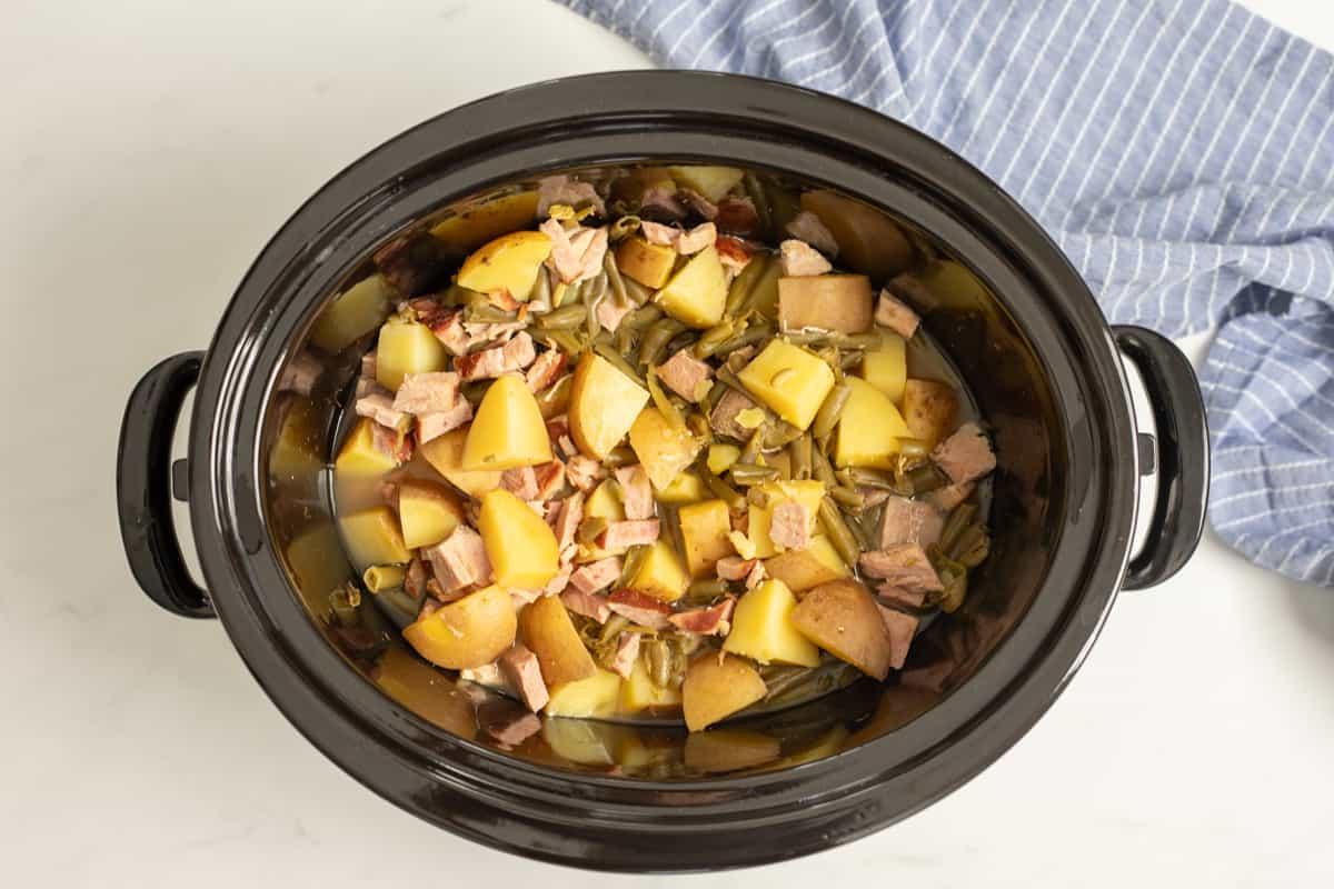 Slow Cooker mit Schinken, grünen Bohnen und Kartoffeln im Inneren.
