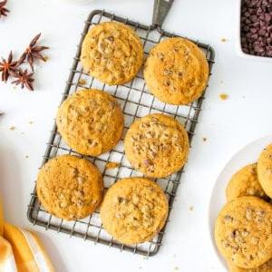 Kürbis-Schoko-Splitter-Kekse 3 Kürbis-Schoko-Cookies auf einem Abkühlgitter mit einem Glas Milch im Hintergrund.