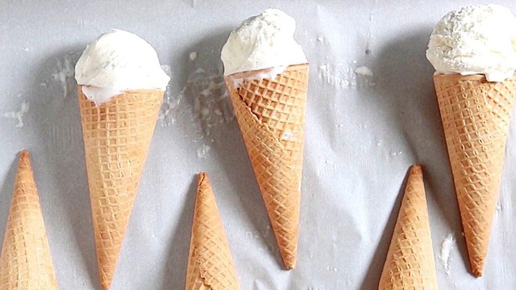 Eiswaffeln mit Vanilleeis auf einem mit Backpapier ausgelegten Blech.