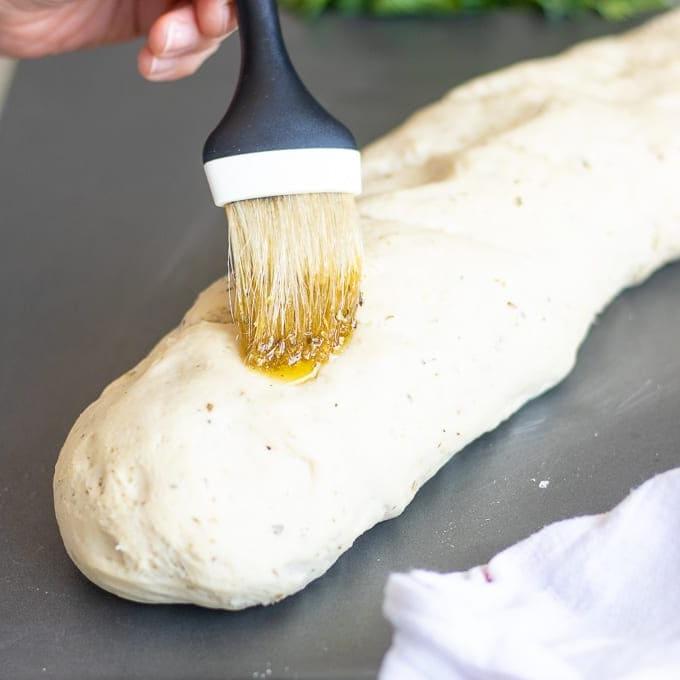 Einfaches italienisches Brot Olivenöl wird auf italienischen Brotteig gestrichen.