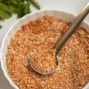 Nahaufnahme von gemischtem Dry Rub in kleiner weißer Schale mit Löffel, der Dry Rub zeigt.