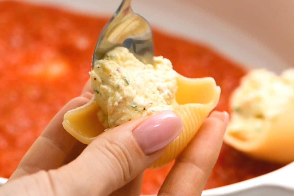 Italienisch überbackene Muscheln Löffel füllt Nudelschale mit Ricotta-Mischung.