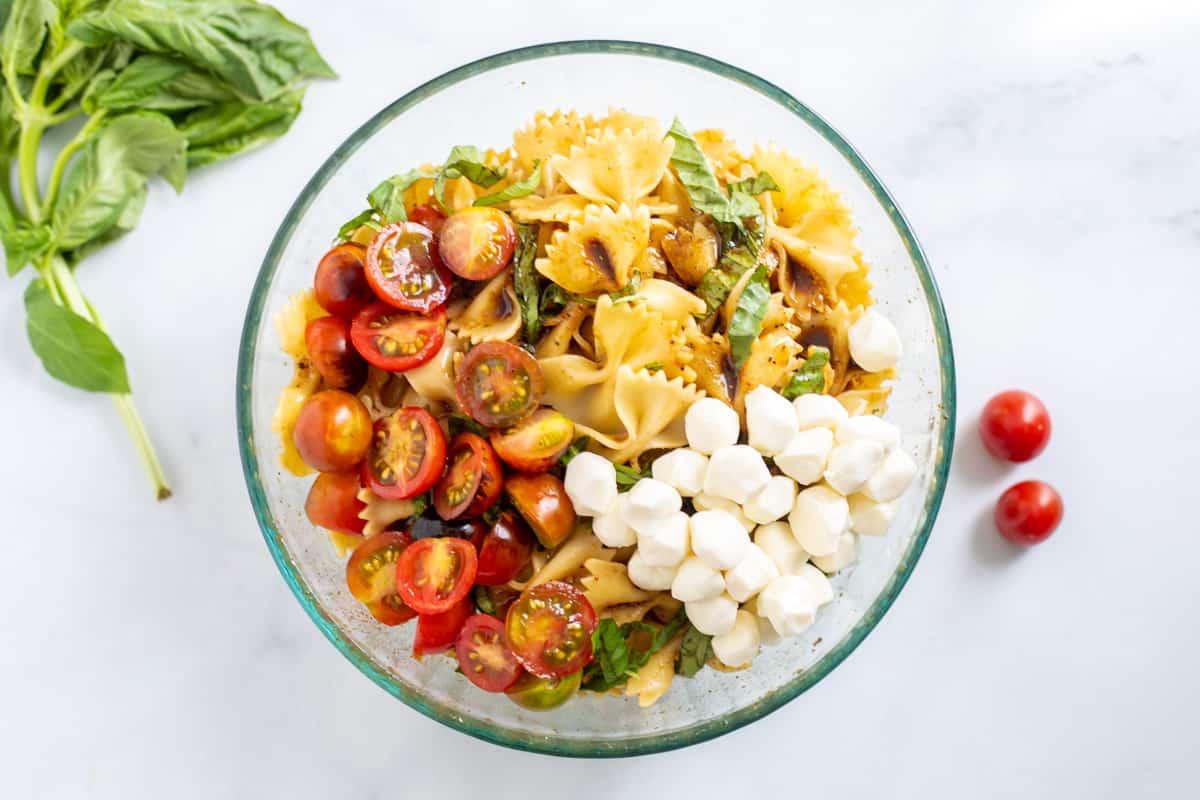 Mozzarella, Tomaten, Basilikum und Nudeln vermischt in einer Schüssel.