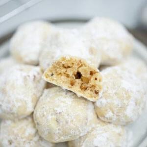 Servierplatte mit Schneeballkeksen, einer davon halbiert, um die Pekannüsse im Inneren zu zeigen.