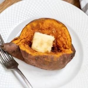 Gebackene Instant Pot Süßkartoffel auf weißem Teller mit einem Stück Butter.