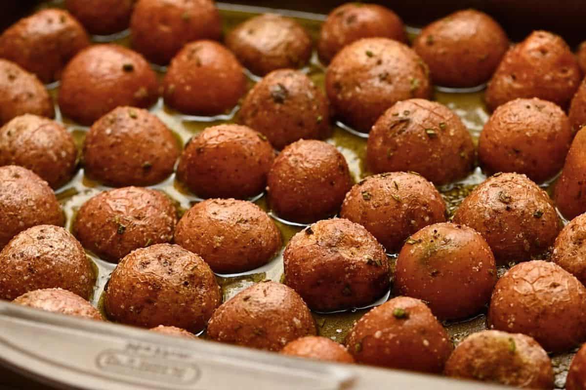 Gewürzte rote Baby-Kartoffeln mit der Schnittfläche nach unten auf dem Backblech.