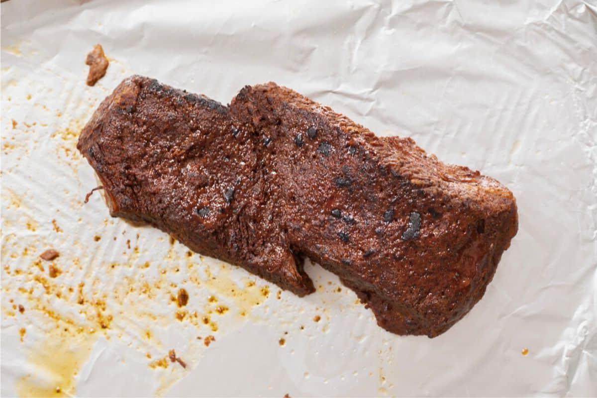 Gegrilltes Instant Pot Brisket auf einem mit Folie ausgelegten Backblech.