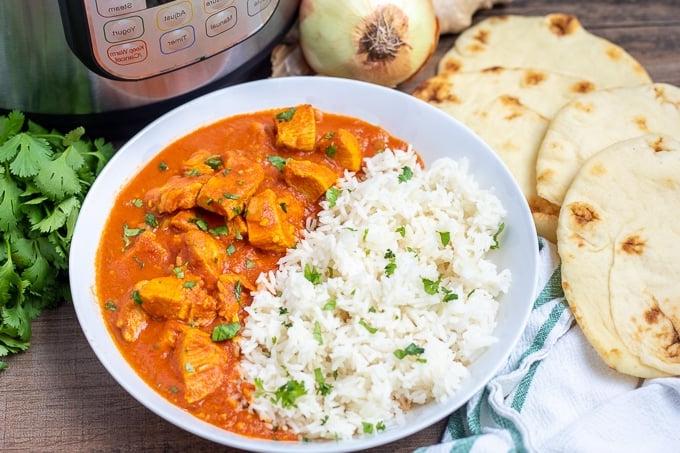 Schüssel mit Butter Chicken neben Naan Brot und Instant Pot.
