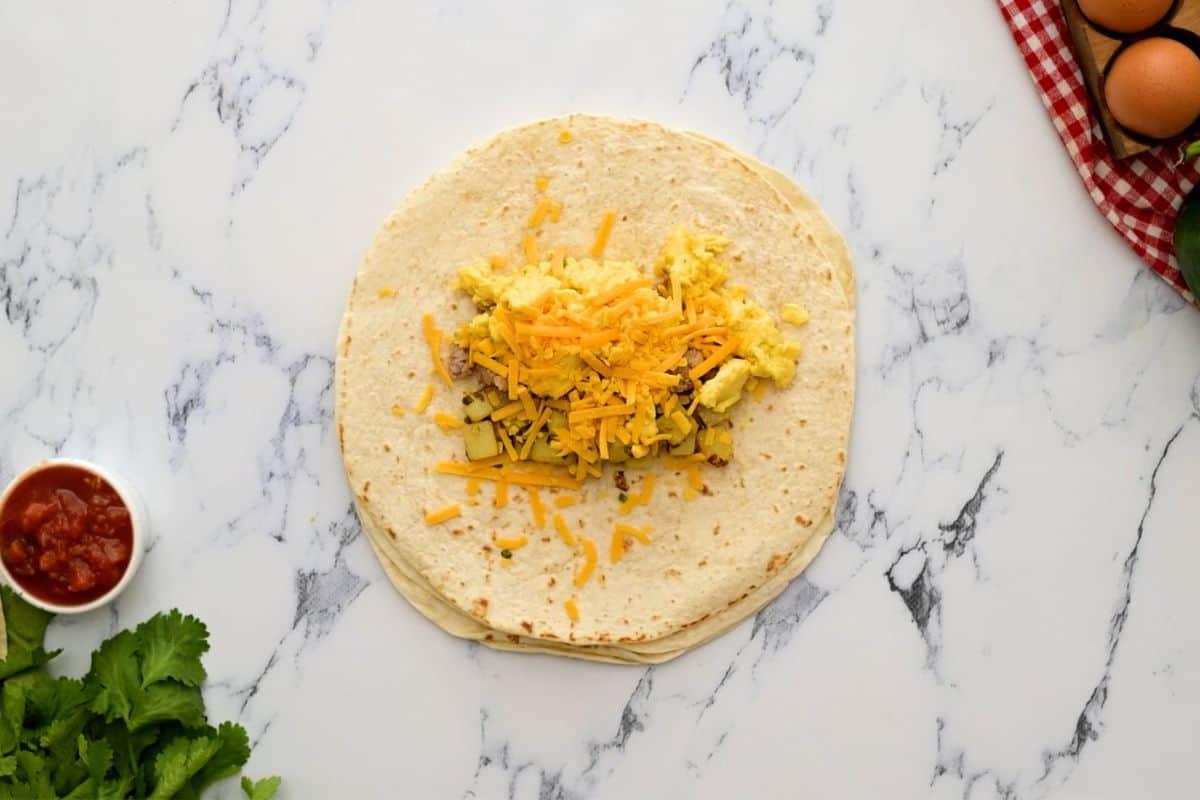 Weizen-Tortilla, mittig mit Kartoffeln, Eiern, Wurst und Käse belegt.
