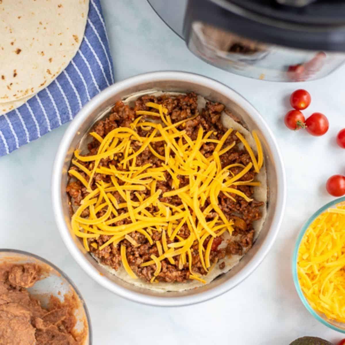 Schicht Taco Pie mit Taco-Fleisch und Käse in der Kuchenform.