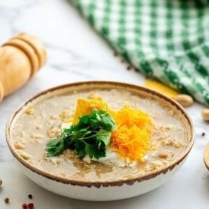 Schüssel mit weißem Hähnchen-Chili, garniert mit Sauerrahm und geriebenem Cheddar.