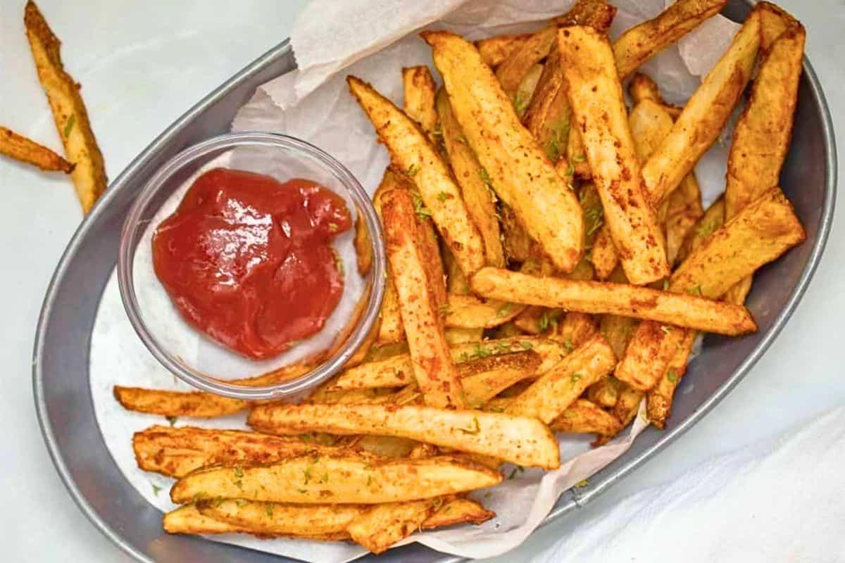 Ein Korb mit knusprigen Pommes aus der Heißluftfritteuse, serviert mit Ketchup.