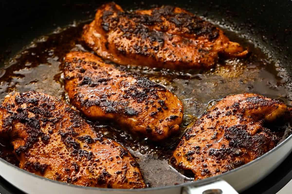 Chicken breasts in skillet after being blackened with Cajun seasoning.