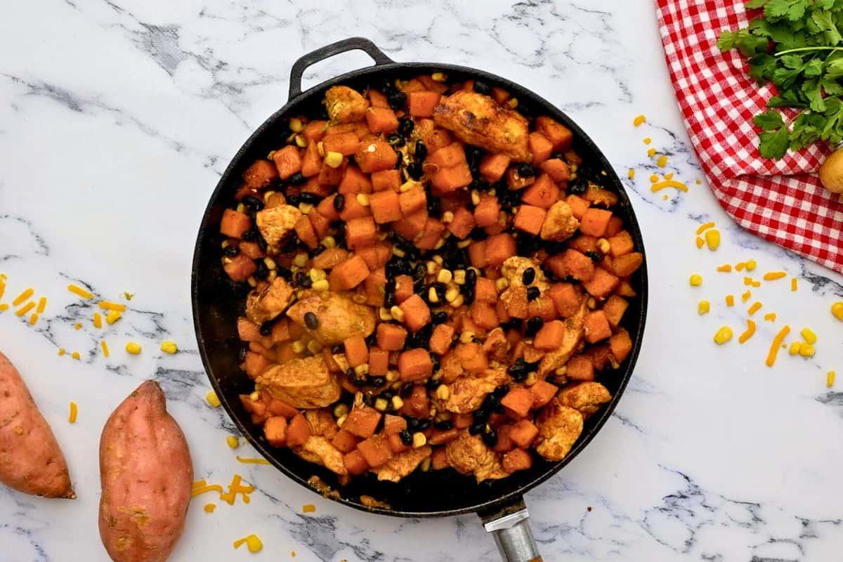 Pfanne mit Süßkartoffeln, Hähnchen, Mais und schwarzen Bohnen vermischt.