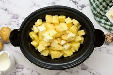 Gewürfelte Kartoffeln, Butter, Brühe und Knoblauch im Slow Cooker.