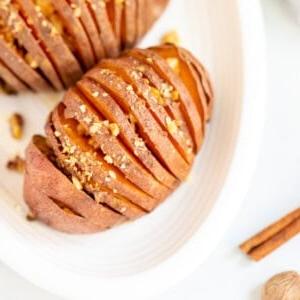 Hasselback Süßkartoffeln 2 Draufsicht auf eine Ahorn-glasierte Hasselback-Süßkartoffel auf einer weißen Platte.