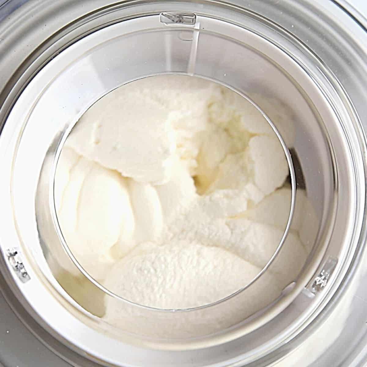 Hausgemachtes Eis für die Eismaschine – Churn-Prozess Gechurntes Eis in der Eismaschine, das seine cremige Konsistenz entwickelt.