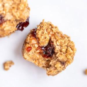 Gebackene Haferflockenmuffins 3 Haferflocken-Muffin mit Marmelade, die aus der Mitte des Haferflocken-Muffins quillt.