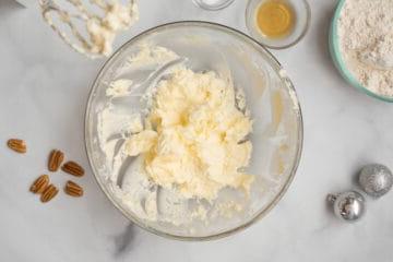 Cremige Butter in einer Rührschüssel neben Pekannüssen.