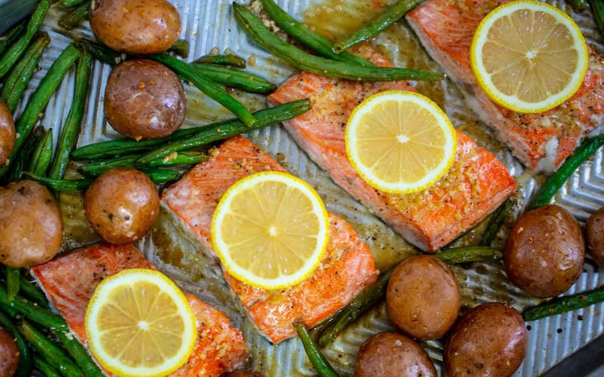 Lachsfilets auf dem Backblech mit grünen Bohnen und Kartoffeln.