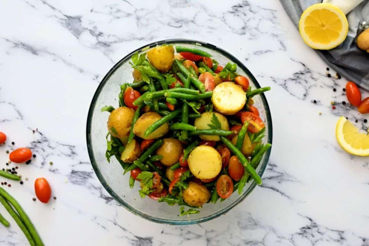 Kartoffelsalat mit Tomaten und grünen Bohnen Zutaten für italienischen Kartoffelsalat in einer großen Rührschüssel vermischt.