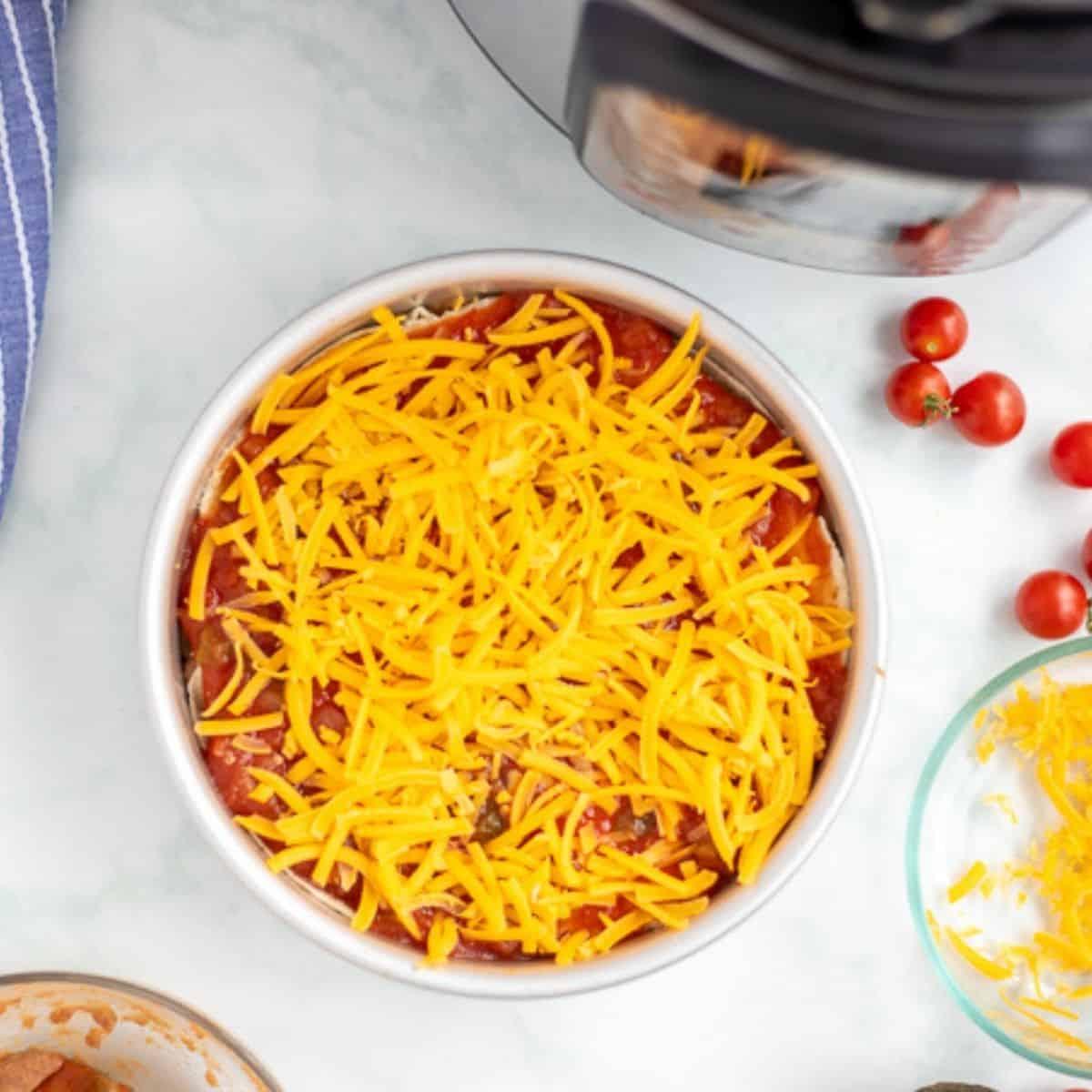 Zusammengestellte Taco Lasagne in der Kuchenform neben dem Instant Pot.