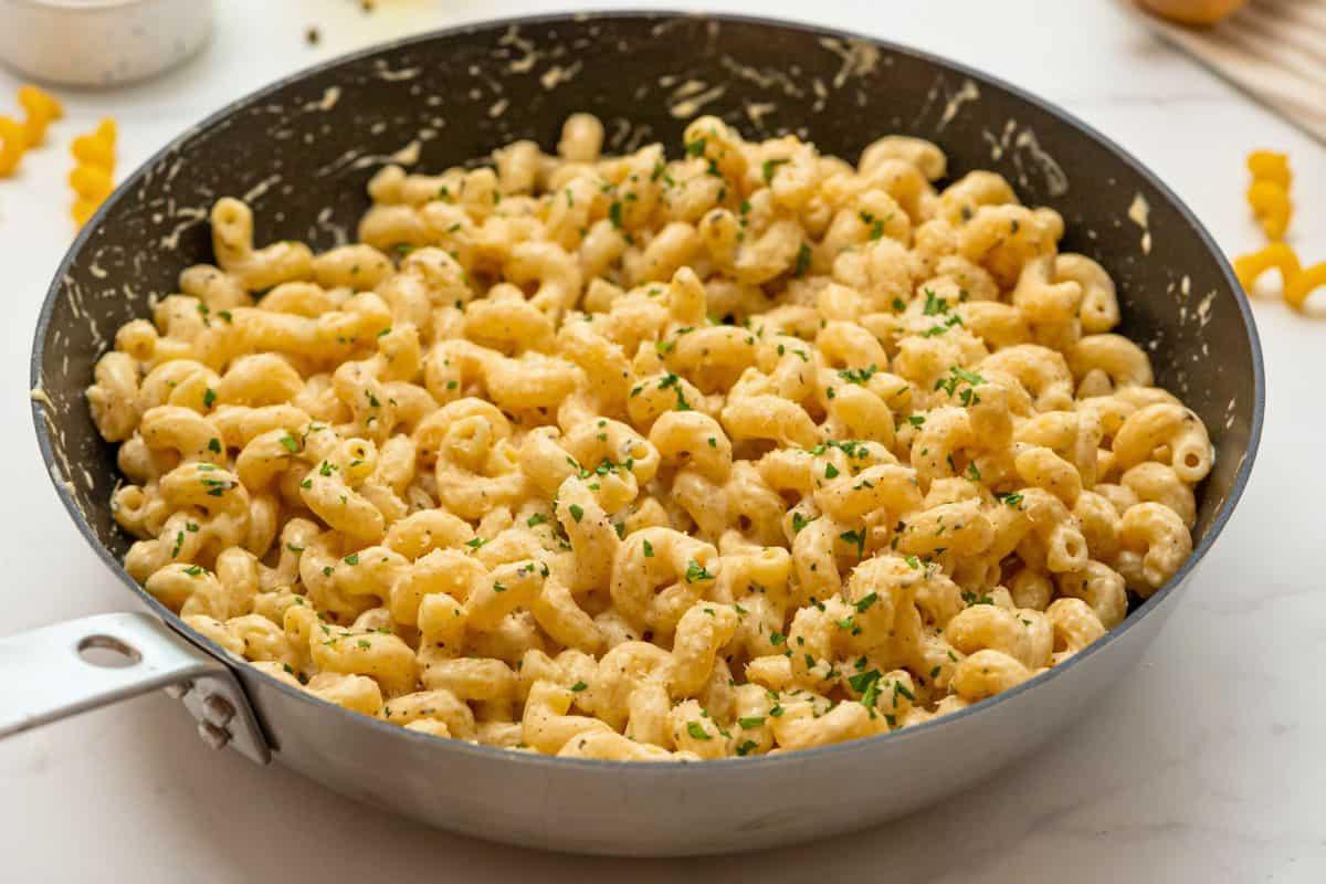 Cavatappi-Nudeln mit Parmesan-Sahne-Soße und gehackter Petersilie in einer Pfanne, appetitlich angerichtet.