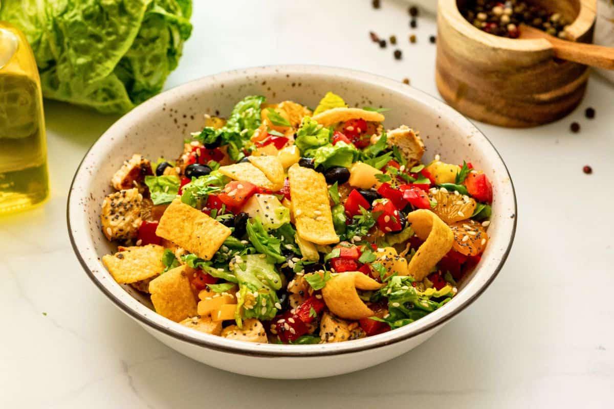 Salat mit gegrilltem Hähnchen, schwarzen Bohnen, Ananas, roter Paprika, Mandarinen und einer Orangen-Vinaigrette.