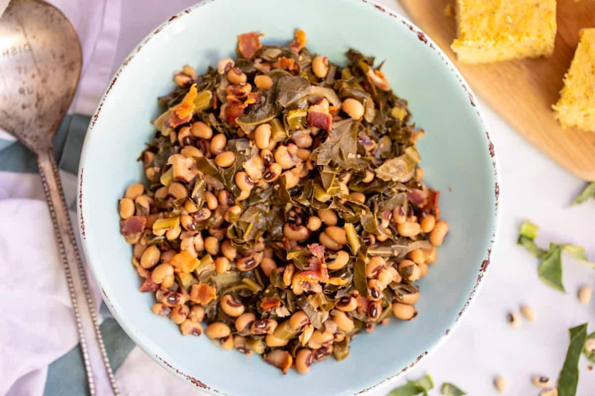 Instant Pot Augenbohnen mit Blattkohl Schale mit Instant Pot Augenbohnen und Blattkohl neben Maisbrot und getrockneten Bohnen.