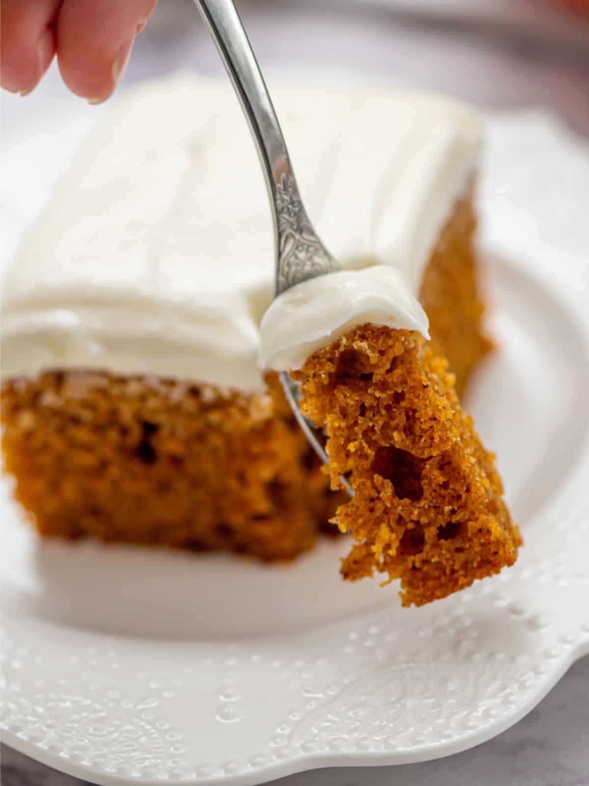Bestes Kürbiskuchenrezept Gabel mit einem Bissen Kürbisgewürzkuchen, der mit Frischkäse-Frosting glasiert ist.