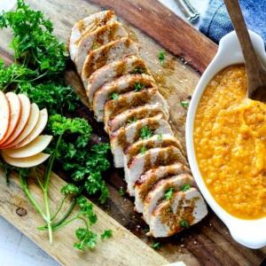 Geschnittenes Schweinefilet neben Süßkartoffelpüree und Äpfeln