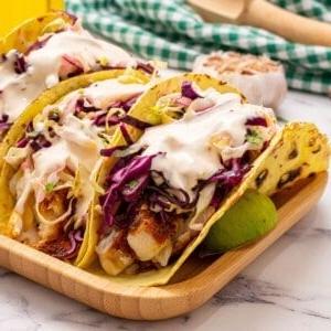 Gesunde Fisch Tacos serviert mit Krautsalat und Crema.